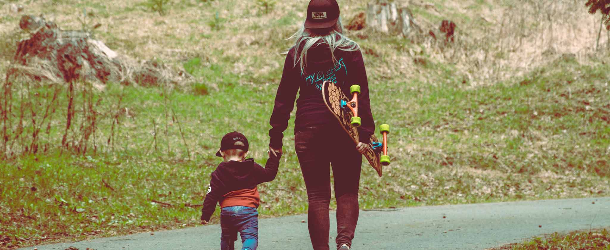 Una donna con uno skateboard accompagna per mano un bambino