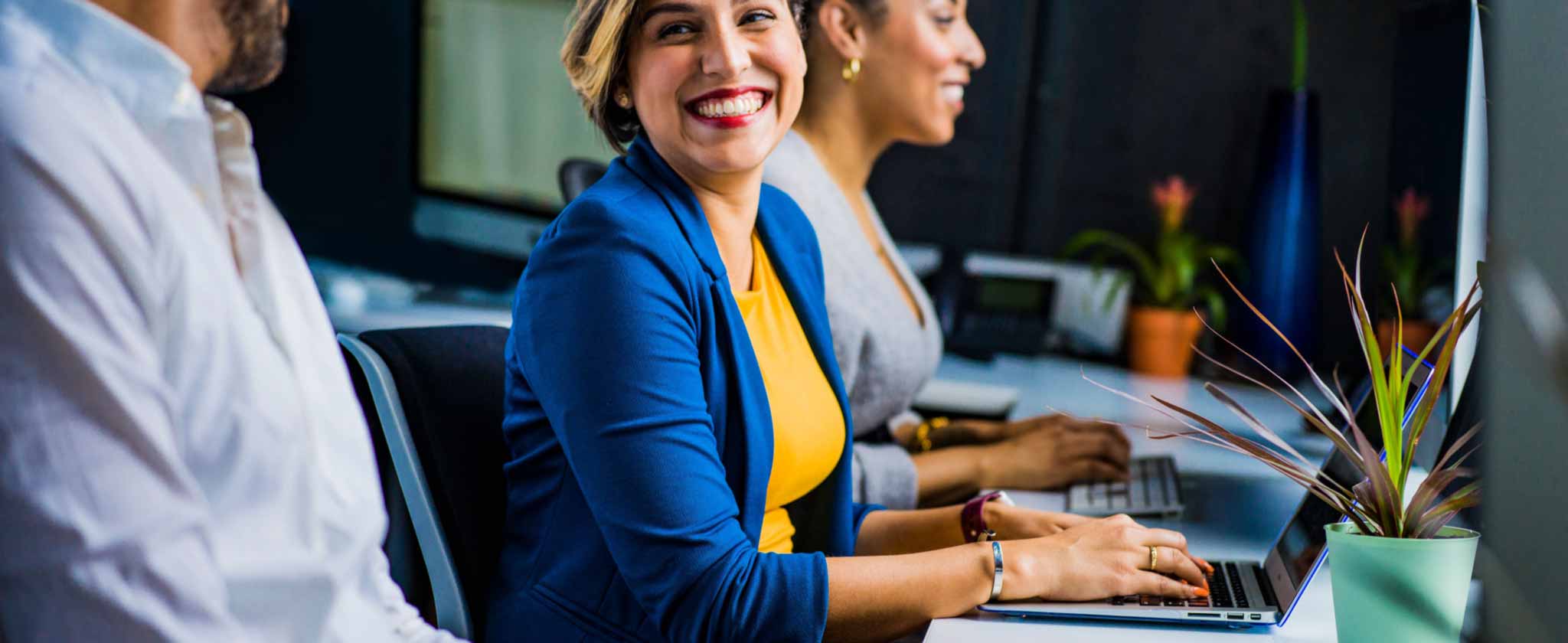 Persone sorridenti al lavoro sui computer portatili in ufficio