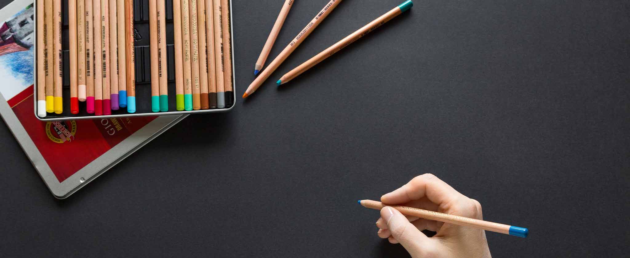Mano che disegna con una matita su un foglio scuro
